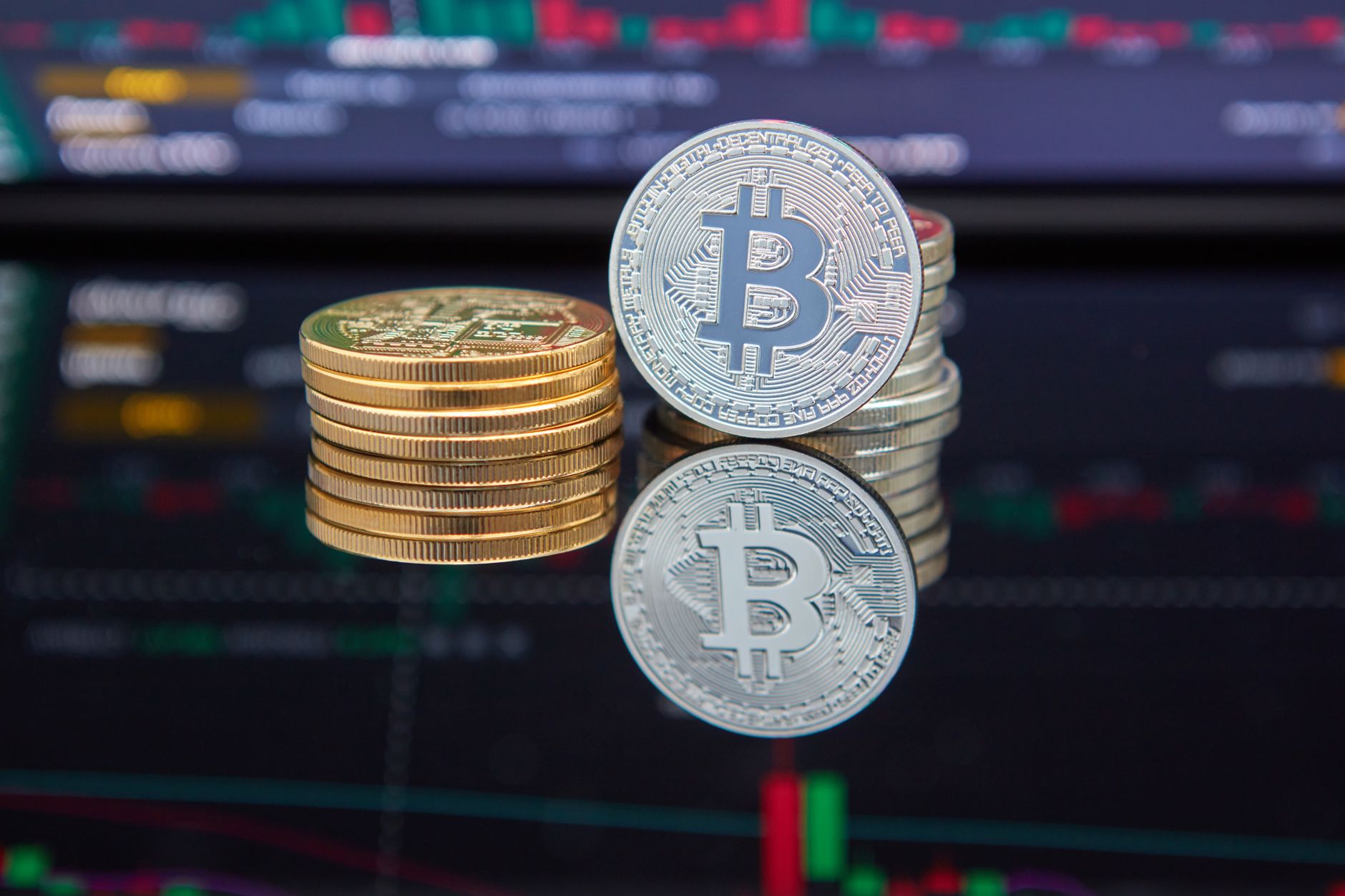 Ilustrasi: Bitcoin coins stacked in front of cryptocurrency trading chart reflecting market trends.